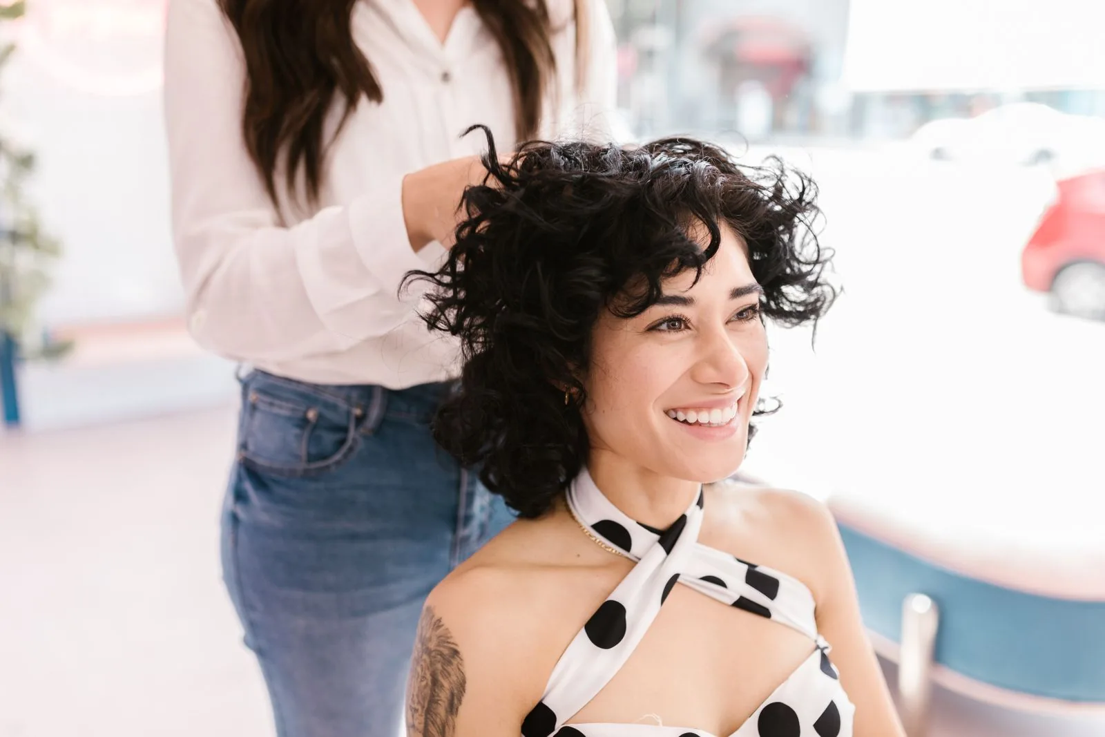 Illustrative stock photograph of a smiling client having her curls styled