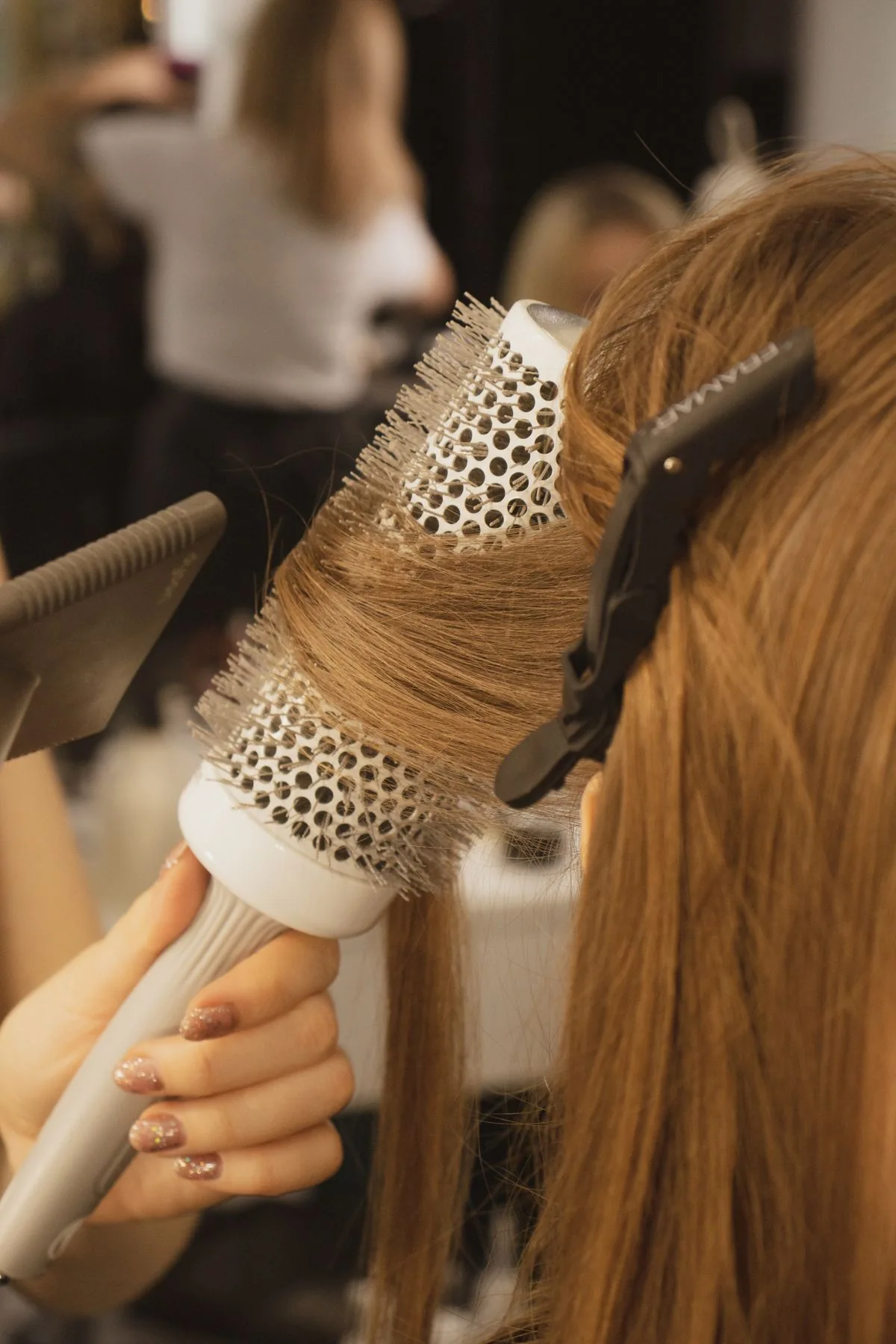 Illustrative stock photograph of copper hair being styled with a round brush